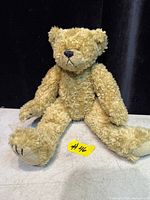 Seated view of tan jointed teddy bear on table
