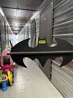 Front view of Batman-shaped wall shelf showing overall shape and shelf bar