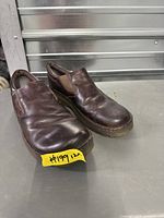 Three-quarter view of both shoes showing uppers, size tag #199, brown leather, slip-on style