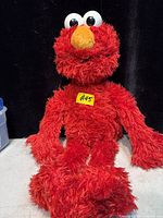 Front view of red Elmo interactive plush toy seated upright