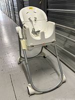 Front view of white Fisher-Price folding high chair showing removable seat and harness straps