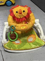Front view of lion Sit-Me-Up floor seat showing frame, padded insert and attached toys