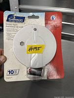 Front view of sealed Garrison smoke alarm package showing product, battery, and warranty