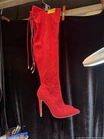 Full view of one red knee-high boot suspended showing overall design