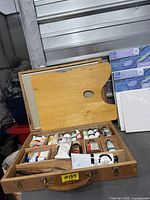 Overall view of Reeves wood case open with palette board, oil paint tubes, canvases beside