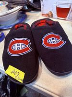 Top view of both slippers showing logo, material and size tag