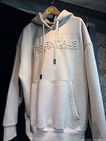 Front view showing ESSENTIALS logo, pocket, hood