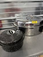 Stainless steel oval roaster and black speckled enamel roaster side by side