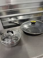 Both pans side by side on countertop, lids visible