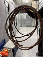 Coiled brown 50' rubber water hose with brass fittings