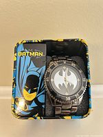 Watch in open tin showing dial, bezel, bracelet, interior foam