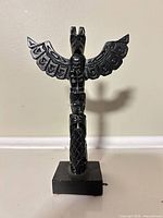 Front view of black resin totem pole on base
