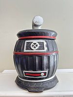 Front view of barrel-style ceramic cookie jar with stovepipe lid