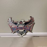 Front view of metal enamel badge showing full design and text