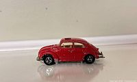 Left side view of red Volkswagen Beetle toy car showing paint wear