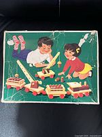 Top of original box showing children with wooden crane and train cars