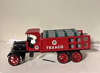 Left side view of die-cast Texaco Kenworth coin bank showing stake bed and barrels