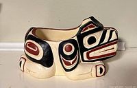 Front right view of cream bear bowl with black/red painted designs