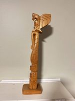 Front view of entire carved totem pole on base