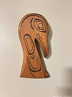 Front view of carved wooden wall hanging showing full bird head design