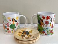Front view of two ceramic mugs and stack of coasters