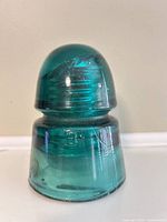 Front view of teal glass insulator showing dome and skirt