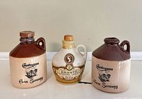 Front view of three miniature jugs showing labels and glazing