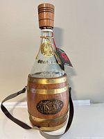Front view of glass decanter in wood barrel sleeve with strap and stopper