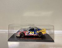Front-side view of diecast car in acrylic case on base