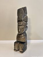 Front view of polished black obsidian seated figure with headdress