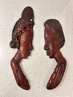 Both carved wood plaques side by side showing profiles