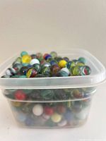 Plastic container densely filled with assorted glass marbles