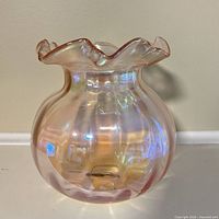 Front view of iridescent pink glass vase with ruffled rim