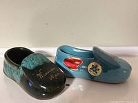 Front and side view of both ceramic moccasins showing inscriptions and decals