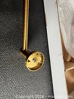 End view of brushed gold towel bar showing round mounting base