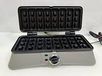 Waffle maker open showing rectangular non-stick grids and control dial