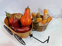 metal wagon filled with faux gourds beside wood bowl with faux corn