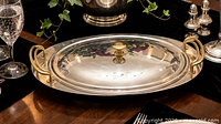Dish on table, lid on, showing gold handles and knob