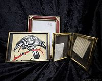 Group of framed art print, burgundy frame, and hinged frames