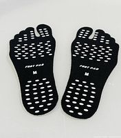 Pair of black five-toe foot pads showing white grip dots and printed size