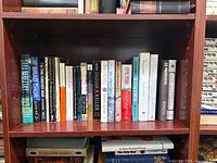 Shelf view of roughly two dozen fiction books showing spines and formats
