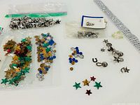 Overall view of bags of sequins, rhinestones, metal studs, prong settings and silver trim