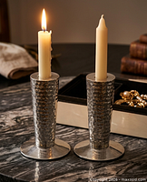 Pair of hammered silver-tone candlestick holders with candles inserted