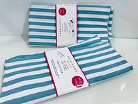 Two folded striped table runners with labels visible