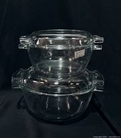 Both clear glass casserole dishes stacked with lids