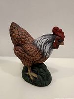 Full side view of ceramic rooster on pedestal