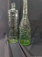 Front view of both bottles showing color difference and embossed designs