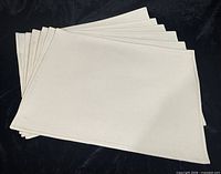 Stack of six off-white cotton placemats, full view
