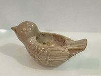 Profile view of beige glazed ceramic bird candle holder