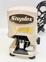 Front view showing Staplex logo, staple slot and caution label